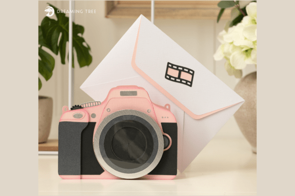 Pink camera-shaped fun fold card with a blank lens, paired with an envelope, ideal for Cricut crafting.