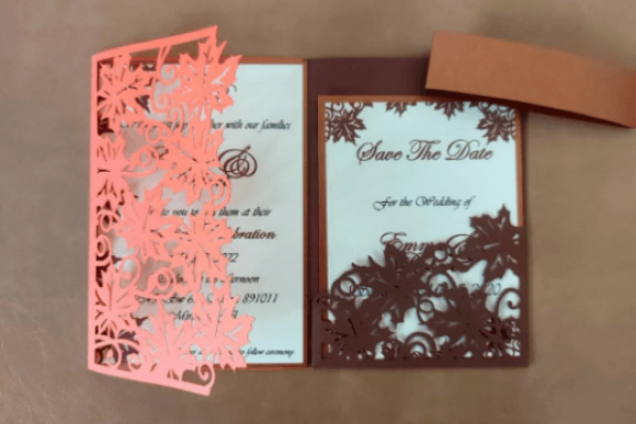 Open tri fold card showing detailed leaf cutouts and wedding invitation text inside.