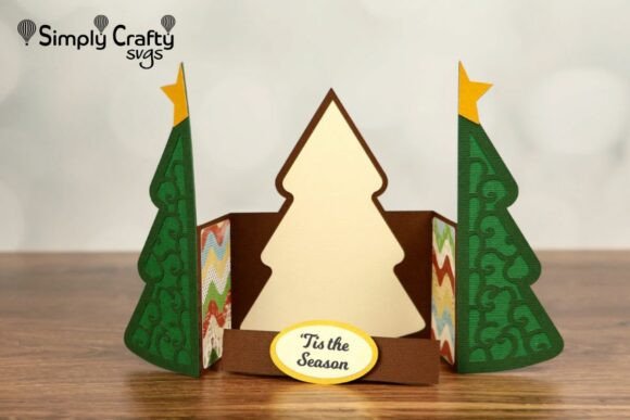 Open Christmas tree card with green swirl sides and 'Tis the Season' label on a wooden surface.