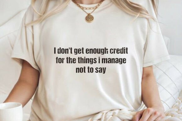 Woman holding a mug, wearing a white t-shirt with the text 'I don't get enough credit for the things I manage not to say.'
