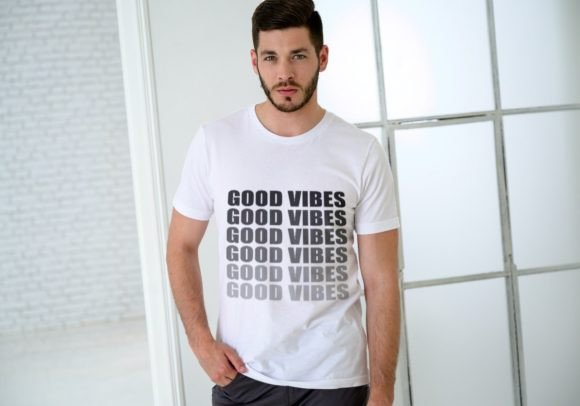 Person wearing a white t-shirt with 'GOOD VIBES' repeated in bold black text.