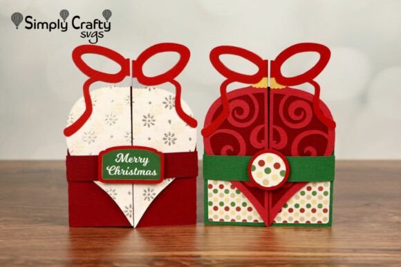 Two ornament-shaped folded cards with bow tops, one red with swirls and one white with snowflakes, both with green accents.