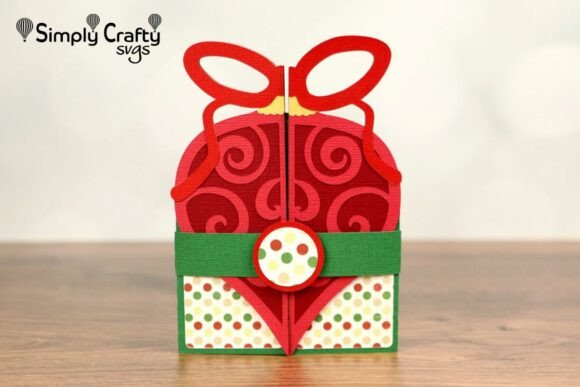 Single red ornament-shaped folded card with swirl pattern, topped with a bow and green band with polka dots.