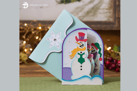 Folded card with three snowmen carolers, snowflakes, and a blue envelope with a white snowflake.