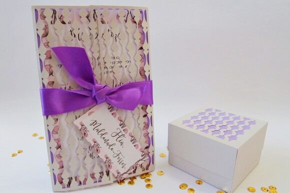 Completed gate fold card with spindle flower design, tied with a purple ribbon, next to a matching gift box.