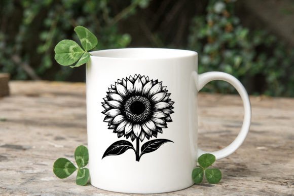 White mug featuring a black and white sunflower illustration, surrounded by small green leaves on a wooden surface.