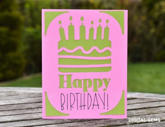 Pink card featuring a green cake cutout with candles and 'Happy Birthday!' text.