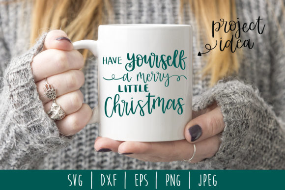 White mug with 'Have Yourself a Merry Little Christmas' in green, held by person in cozy sweater, for Cricut projects