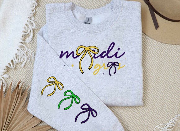 Gray sweatshirt featuring 'mardi gras' text with bows in purple, yellow, and green on the sleeve.