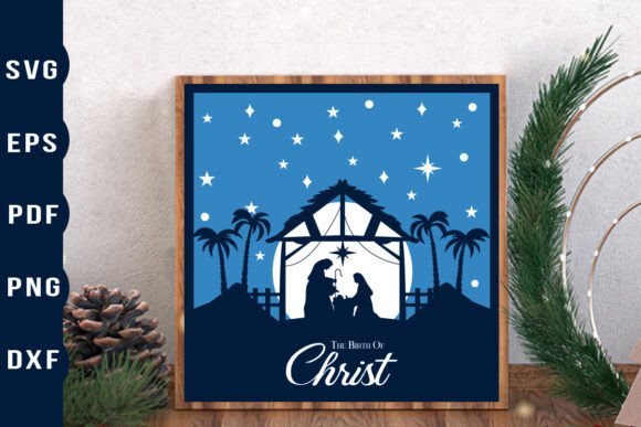 Framed nativity scene with stars, palm trees, and 'The Birth of Christ' text, next to pine branches and pinecones.