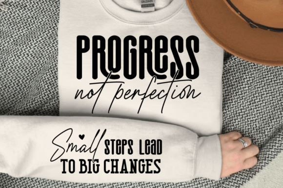 White sweatshirt laid flat with 'Progress not perfection' on front and 'Small steps lead to big changes' on sleeve.
